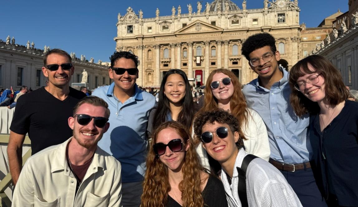 A group of students smile in front of the Vatican