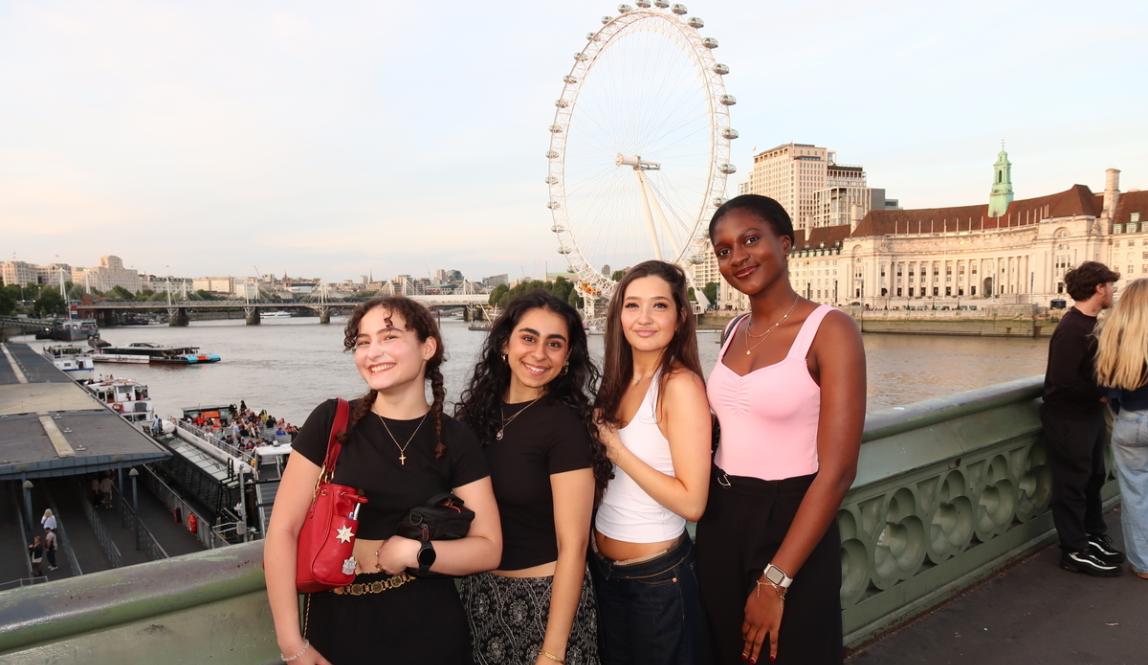 A group of friends smiling on a bridge in front of the London Eye