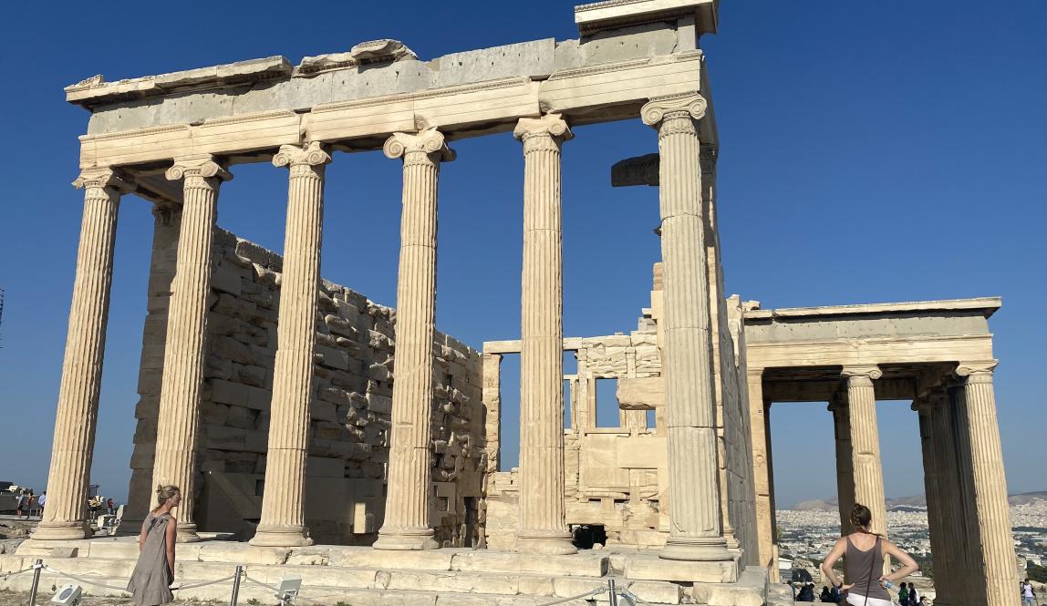 Ancient Greek temple ruins with tall columns under a clear blue sky. This alt text was added with Al; accuracy may vary.