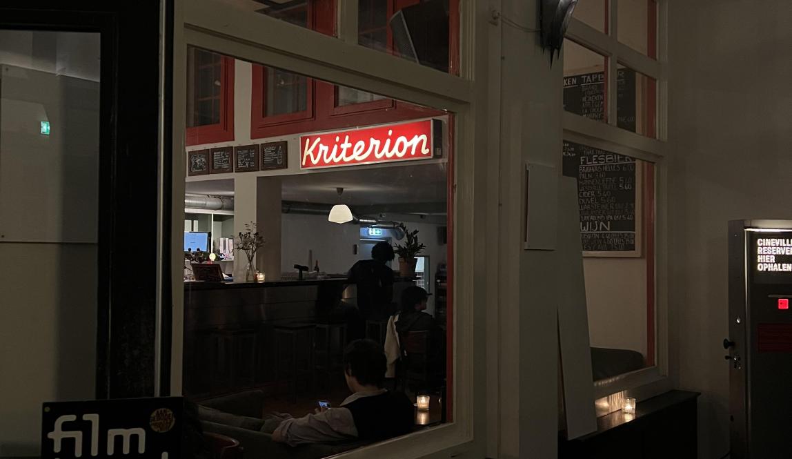 A cozy, dimly lit bar with a red neon sign that reads 'Kriterion.'