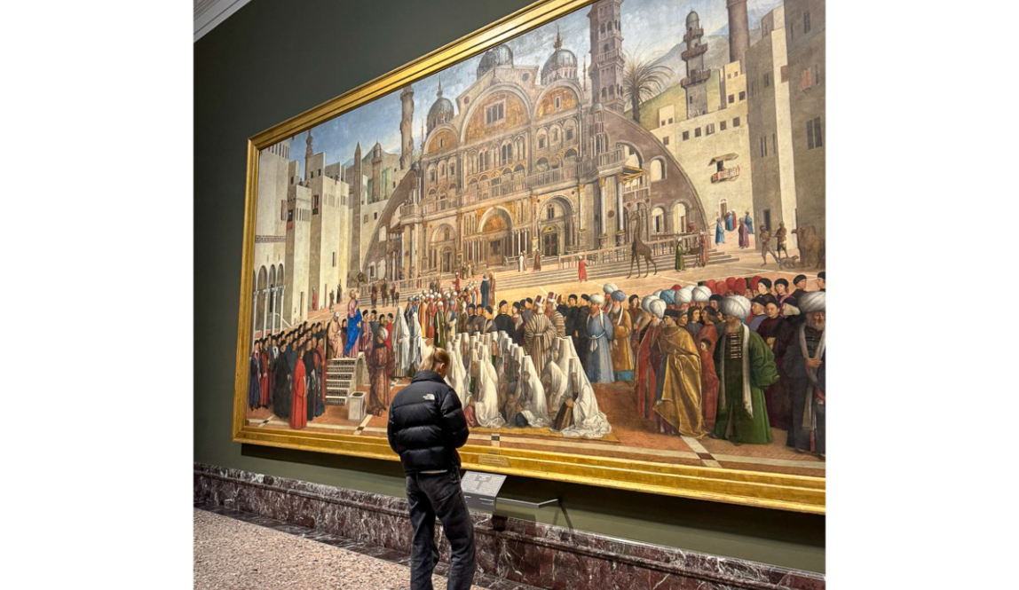 A person standing in front of the large painting St. Mark Preaching in Alexandria at the Pinacoteca di Brera in Milan.
