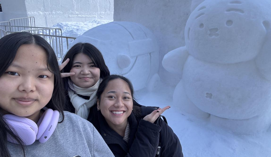 My friends and I taking a selfie in front of a cute tiger snow sculpture at the Sapporo Snow Festival