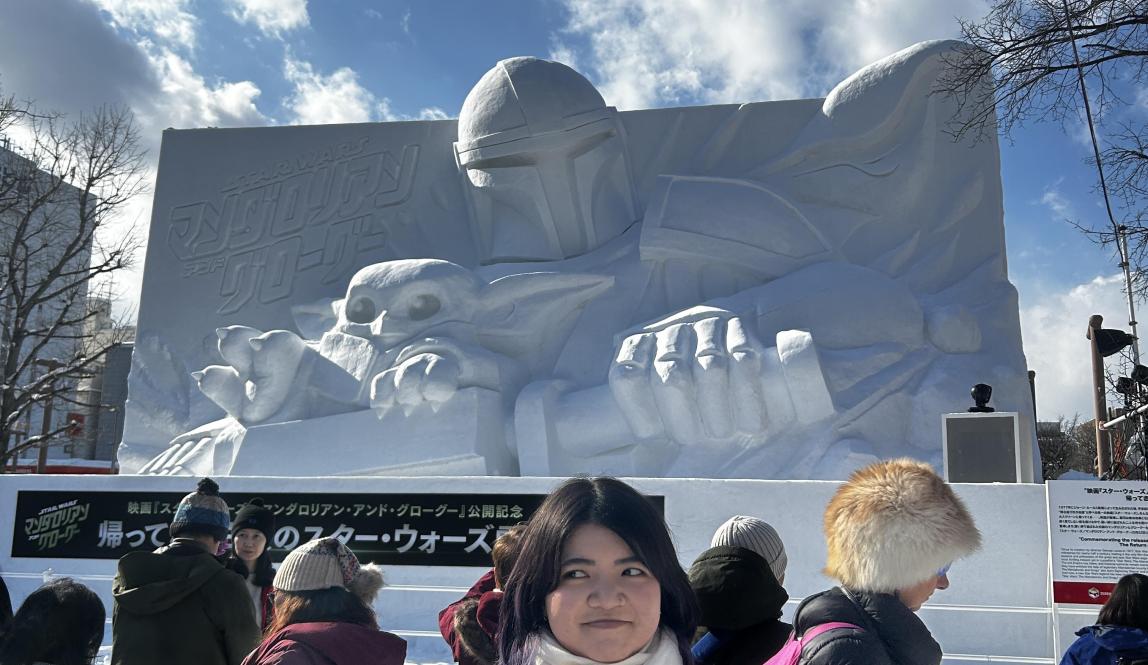 Me posing in front of a huge snow sculpture of the Mandalorian from Star Wars