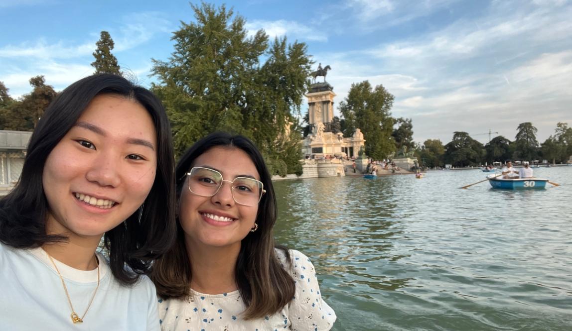 Two students smiling in front of the water at Retiro Park in Madrid, Spain