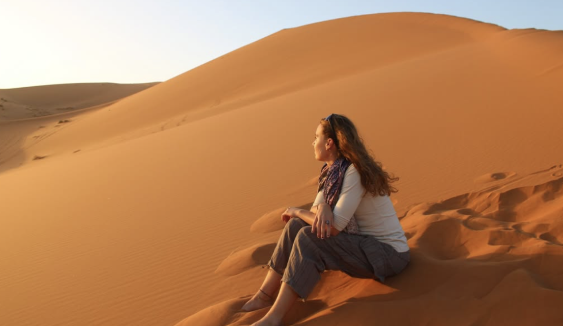 Student sitting in the desert looking out