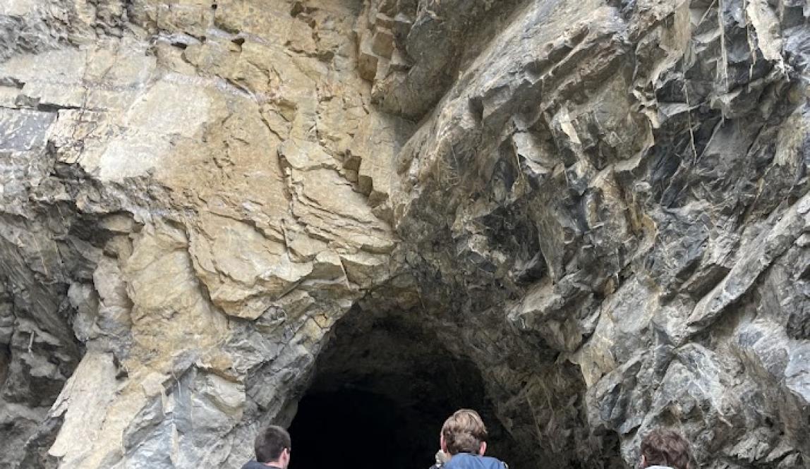 People entering a cave wearing backpacks