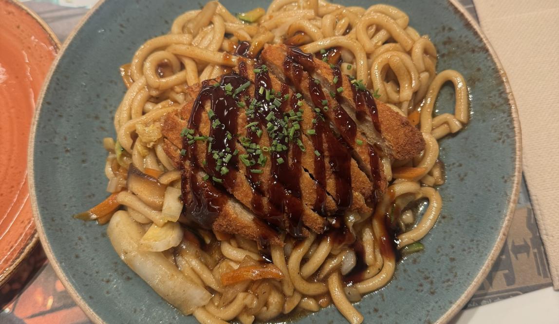 Plant-Based Chicken on top of stir-fried udon noodles and vegetables from UDON