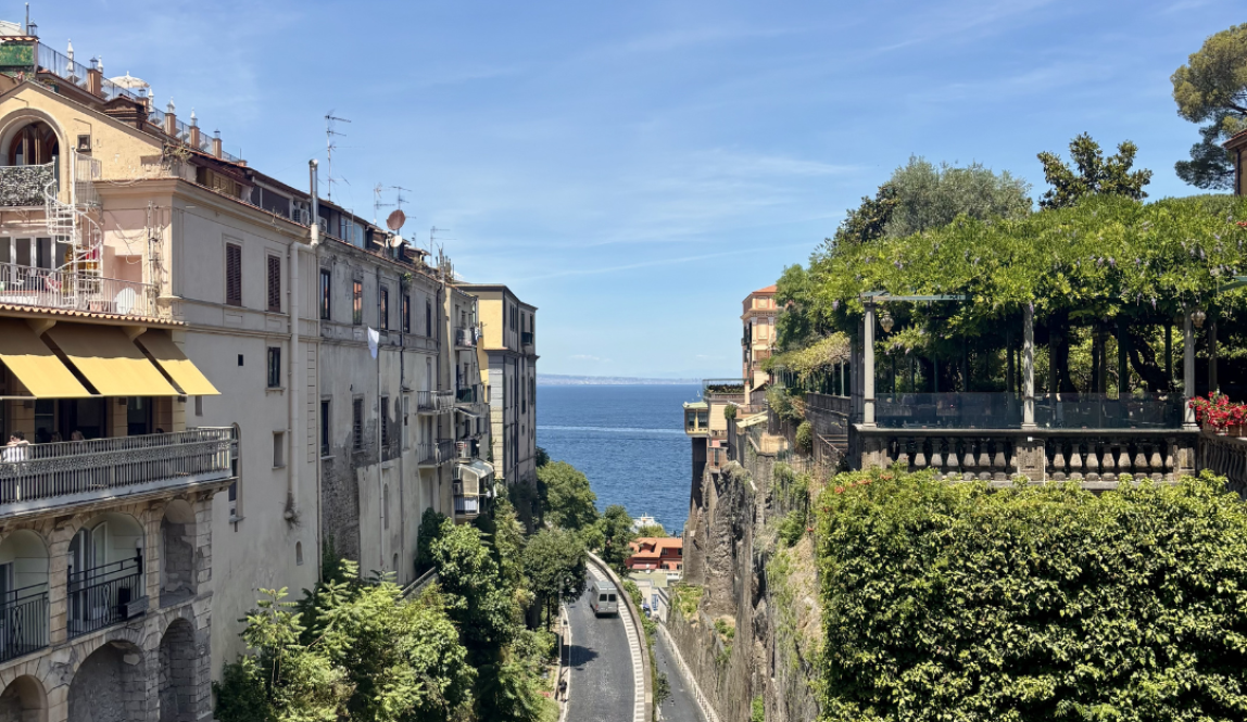 Two cliffs lining a road at the bottom with a view of the sea