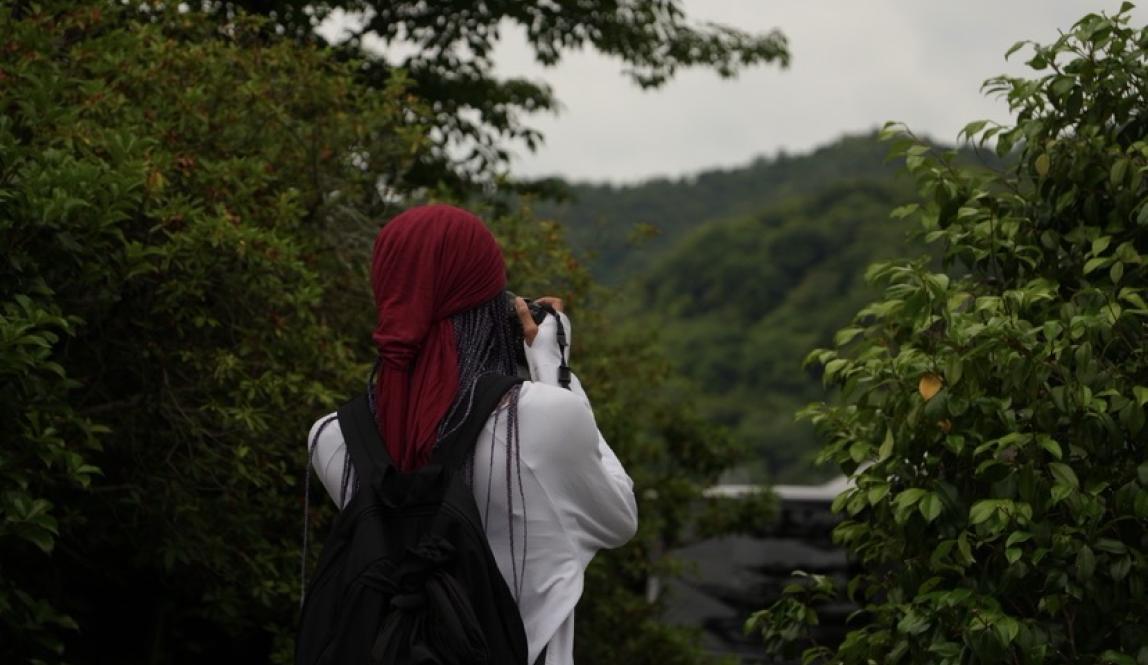 MJ Sails looking at a view in Osaka and taking a picture.