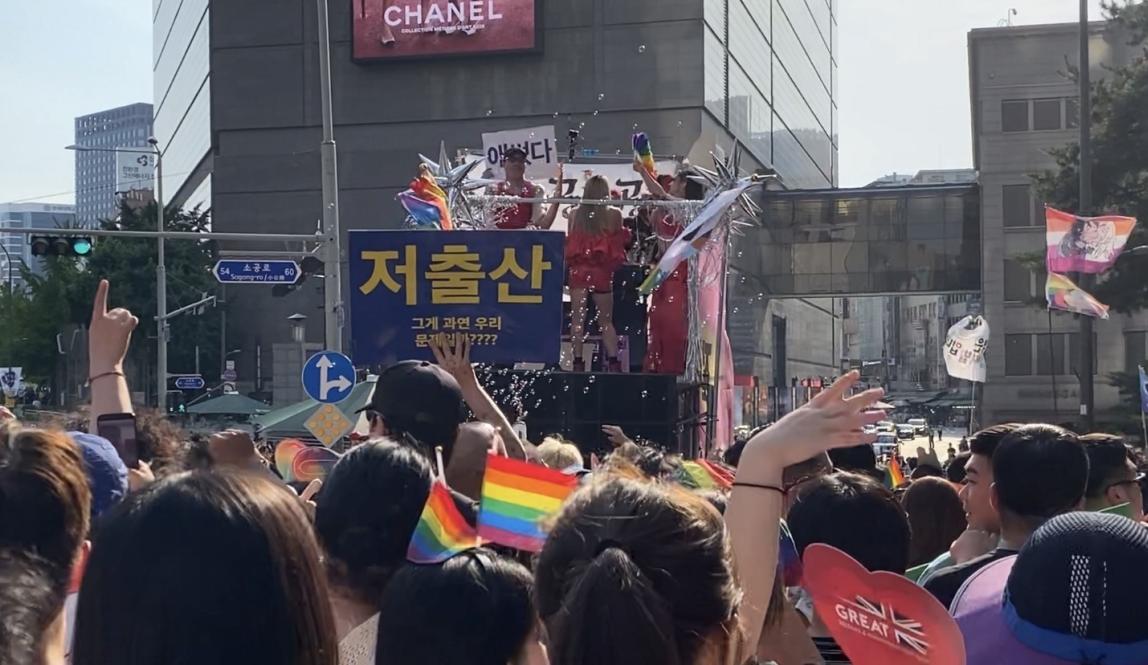 An image of the Seoul Queer Culture Festival crowd witch performers dancing on top of a moving float.