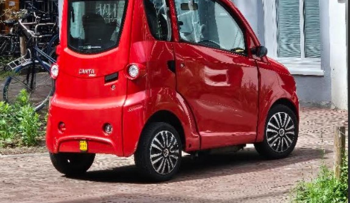 A 4-wheeled parked red vehicle that only hosts 2 people. 