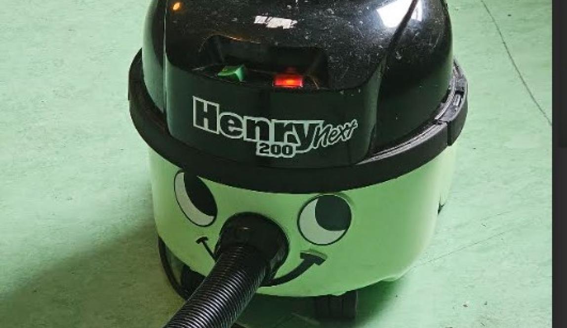 A mint green vacuum shaped like a pot with a black bowler hat with the hose for the nose. 