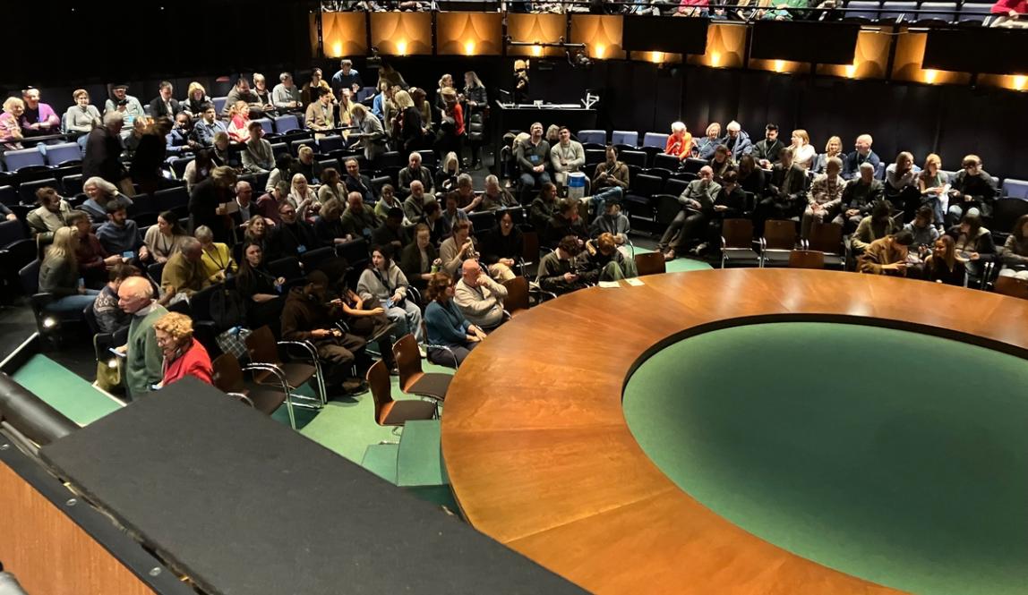 Theatre students sitting around a round theatre production stage.