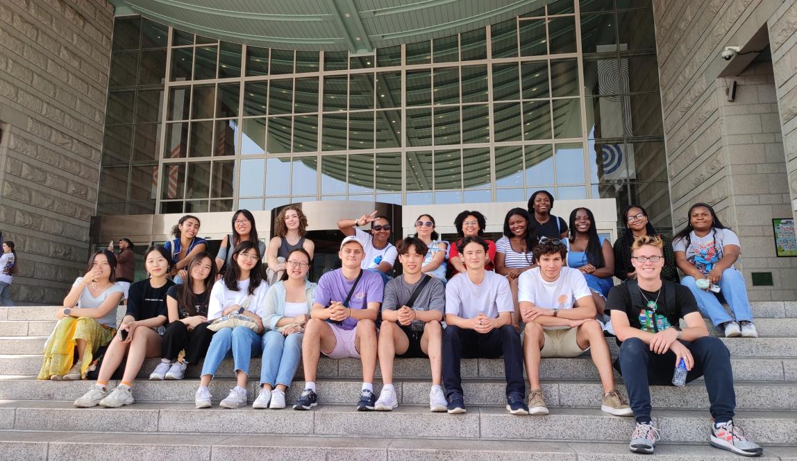 Students sitting on the steps and smiling while in Seoul, South Korea.