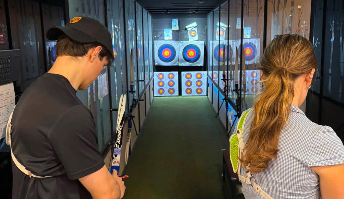 Writer practicing archery in an archery lesson. 