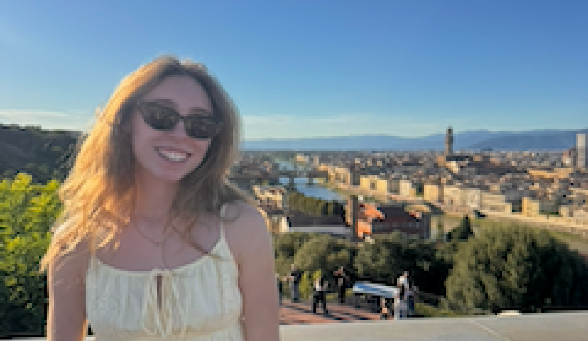 A girl smiling at the top of the Piazzale Michelangelo with a view of Florence in the background