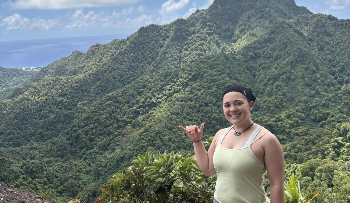 Pono at the top of the Te Rua Manga outlook with other mountains in the background.