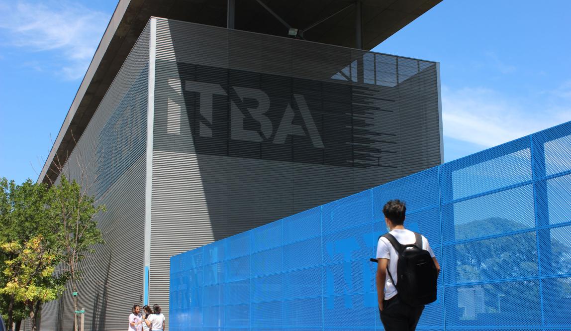 a student wearing a backpack walking toward an ITBA building