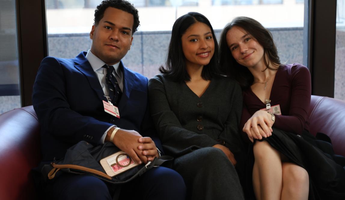 Three students sit in business professional attire on the EU Member States trip to Brussels, Belgium.