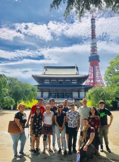 students posing for a photo in front of Tokyo Tower and a Japanese palace