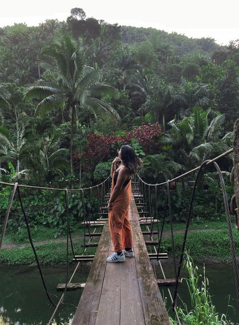 A student walks across a narrow wooden bridge.
