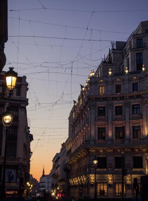 Between two white buildings lining a street in Madrid at night.
