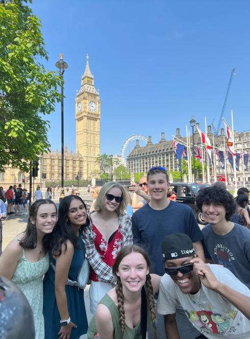 group of london students huddled together in front of big ben, london eye, and other notable london landmarks