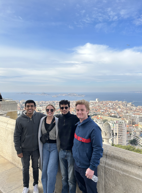 Four students at viewpoint in Nice, France - posing with city and ocean behind them 