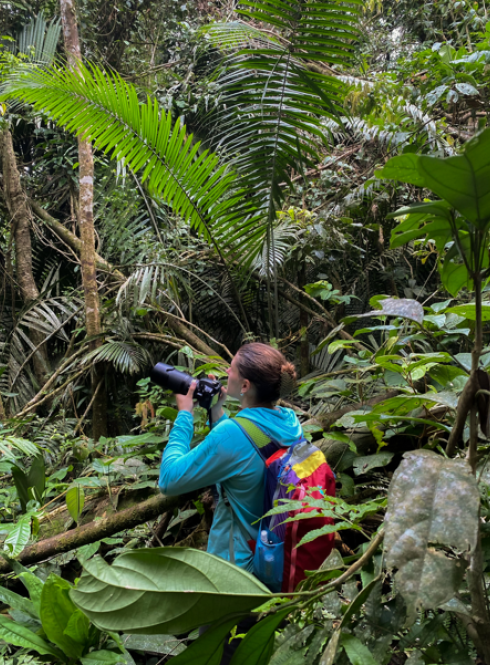 Student holding a camera in the jungle