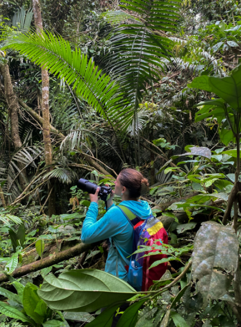 Student holding a camera in the jungle