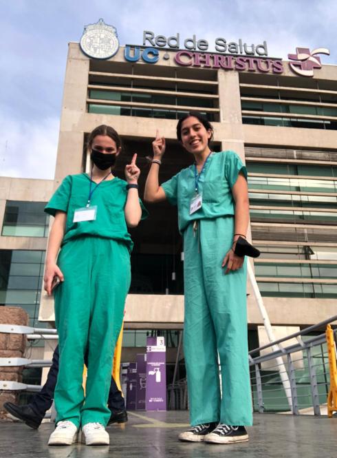 two female students in scrubs pose for a photo outside of their clinical observation