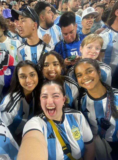 a group of students in Argentina futbol jersey's in a crowd