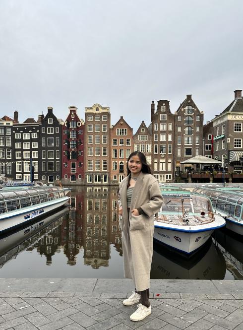Student standing in front of Boats and Rows of Houses in Amsterdam Canal