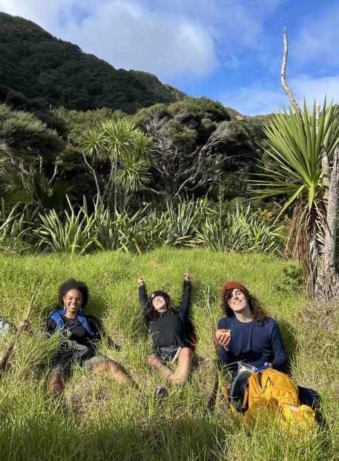 Three students laying in the grass while on a hike in New Zealand's mountains