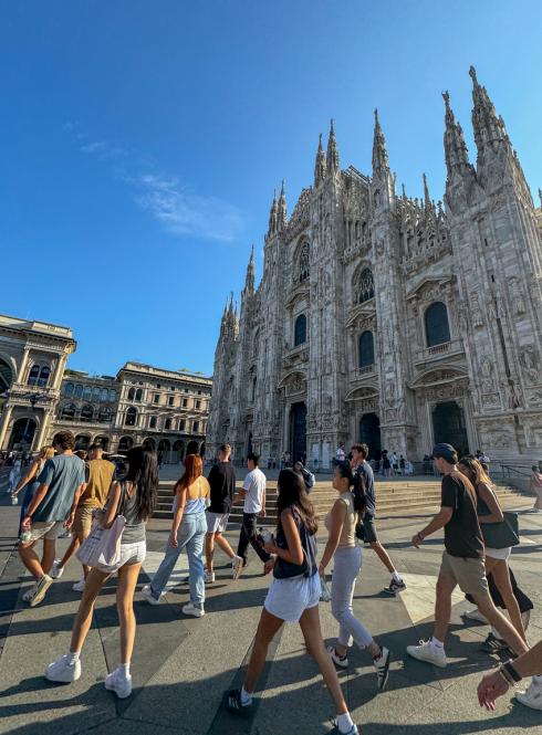 Group of students walking past the Duomo in Milan on a sunny morning