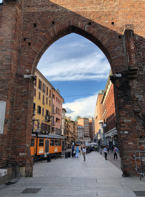 A bustling Milan street as viewed through a historic archway