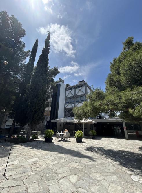 Modern building surrounded by trees under a clear blue sky. This alt text was added with Al; accuracy may vary.