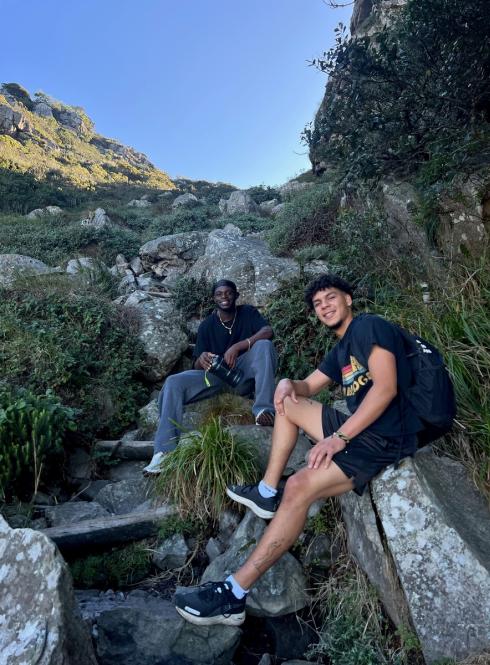 Two guys sitting on rocks in front of a blue sky in Cape Town.