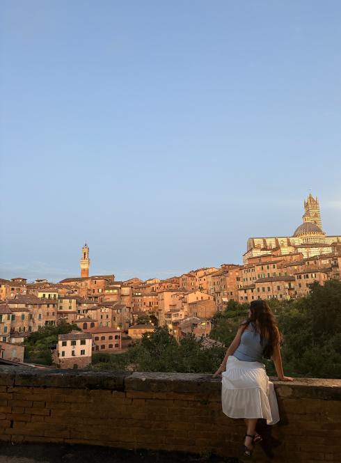 A student sitting on a ledge overlooking the city of Siena, Italy