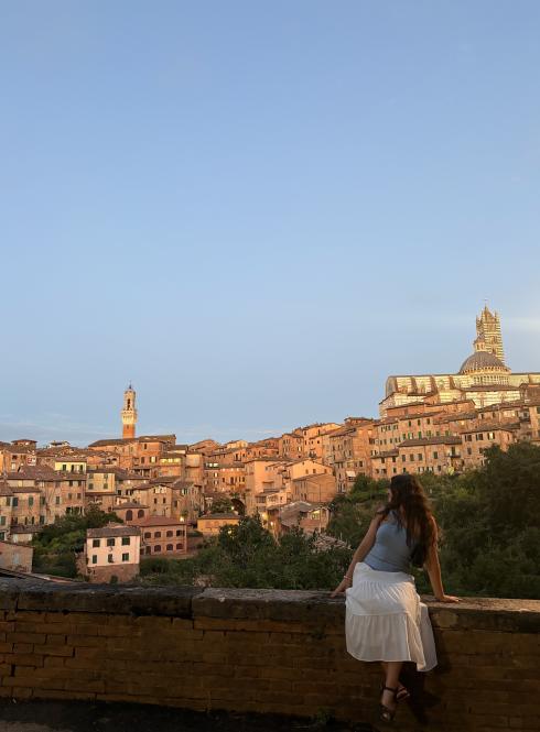 A student sitting on a ledge overlooking the city of Siena, Italy