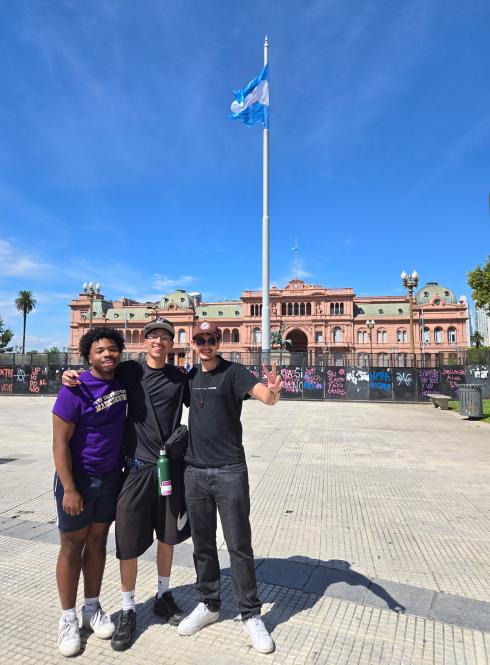 three students standing in front of La Casa Rosada