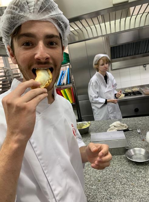 a student eating an empanada during a cooking class