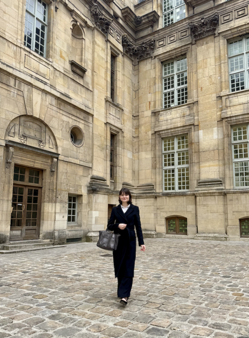 Student in business attire walking in front of parisian building
