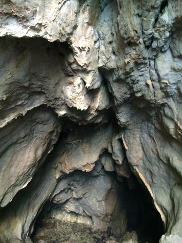 Rocky sea arch with boat beneath on Capri coast. Rugged cave interior with textured rock walls. This alt text was added with Al; accuracy may vary.