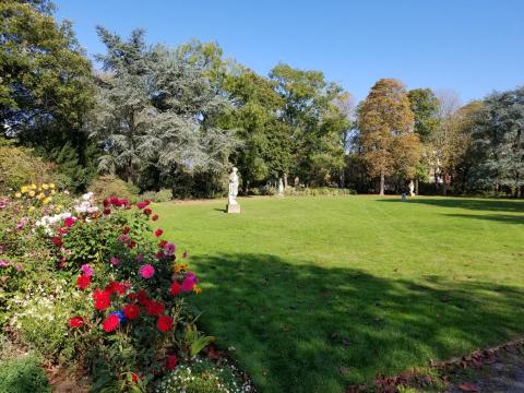 There are statues in the back, and on the left are some dahlia plants. At the right is a large grassy expanse