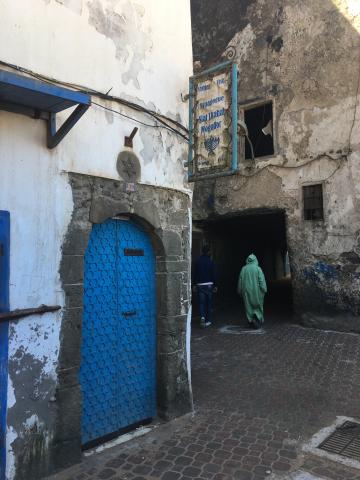 A man in a jalaba passes a synagogue in Essaouira