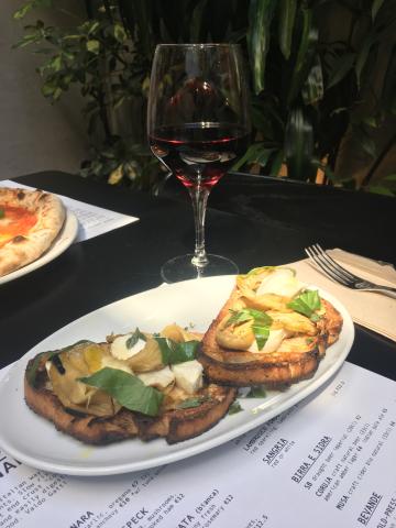 A plate of bruschetta and a glass of red wine