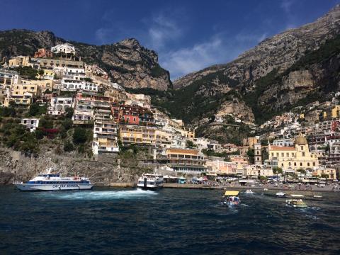 Colorful buildings on Positano's hillside by the sea under a clear blue sky. This alt text was added with Al; accuracy may vary.