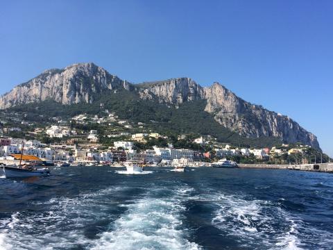 Coastal view of Capri with cliffs and blue sea under a clear sky. This alt text was added with Al; accuracy may vary.