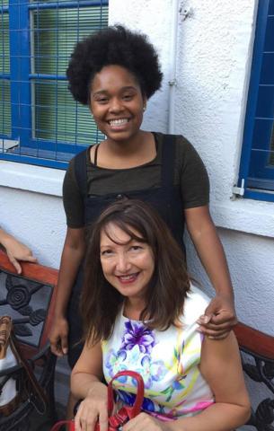 A photo of Robrenisha Williams smiling and sitting in front of the house with her new friend during her homestay 
